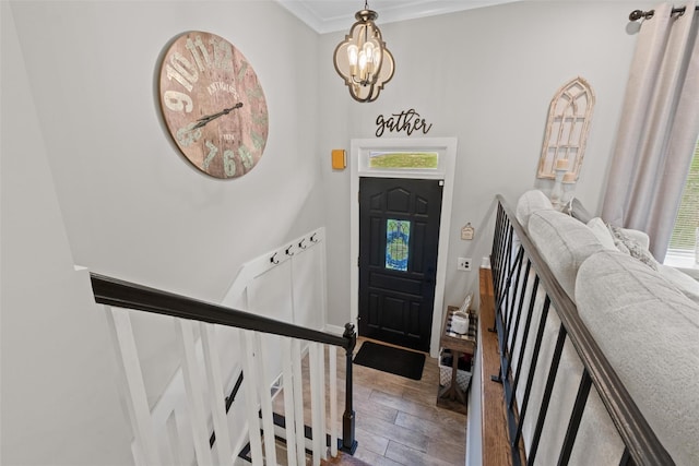 entrance foyer featuring wood finished floors, ornamental molding, plenty of natural light, and an inviting chandelier