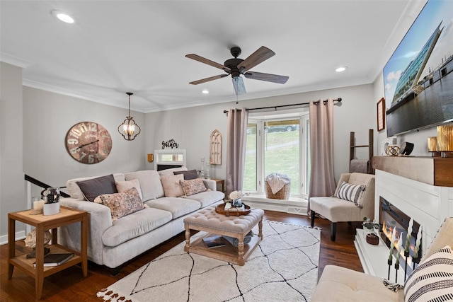 living area with ceiling fan, ornamental molding, a glass covered fireplace, and wood finished floors