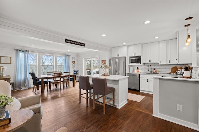 kitchen featuring a center island, stainless steel appliances, a breakfast bar, and a healthy amount of sunlight