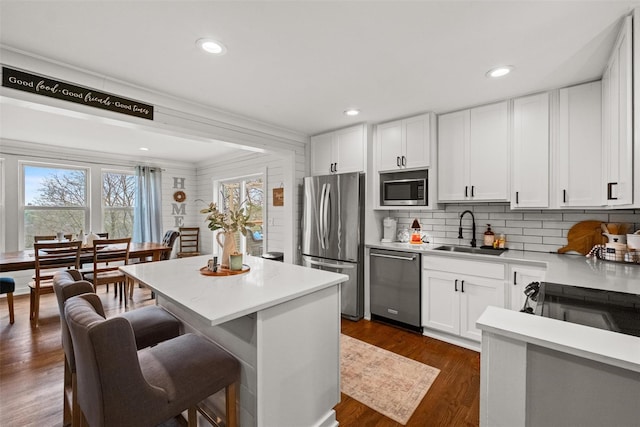 kitchen featuring light countertops, a kitchen breakfast bar, stainless steel appliances, and a sink