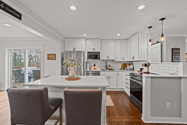 kitchen with stainless steel appliances, a sink, dark wood-style flooring, white cabinetry, and light countertops