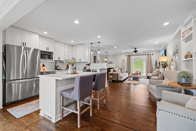 kitchen with dark wood-type flooring, ornamental molding, open floor plan, and stainless steel appliances