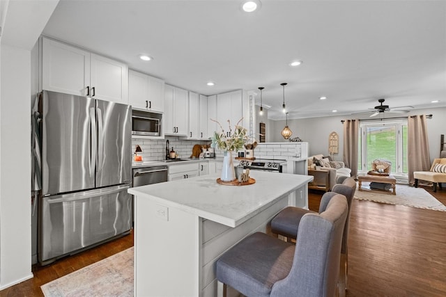 kitchen with dark wood finished floors, stainless steel appliances, a sink, tasteful backsplash, and white cabinetry