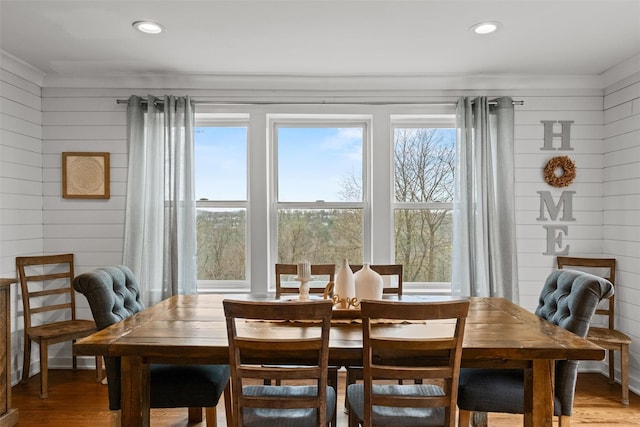 dining space featuring wooden walls, wood finished floors, and a wealth of natural light