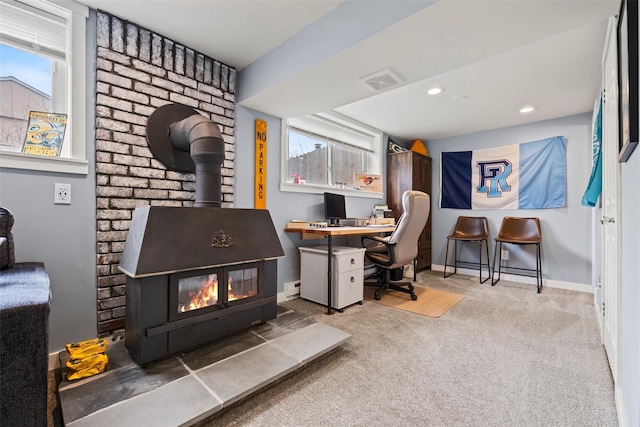 office space with carpet, a wood stove, plenty of natural light, and visible vents