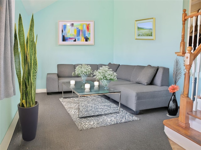 carpeted living area with stairway, baseboards, and vaulted ceiling