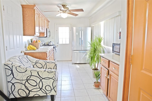 kitchen featuring ornamental molding, light countertops, a ceiling fan, light tile patterned flooring, and appliances with stainless steel finishes