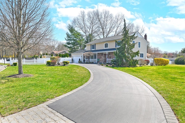 view of front facade with a chimney, driveway, a front lawn, and fence