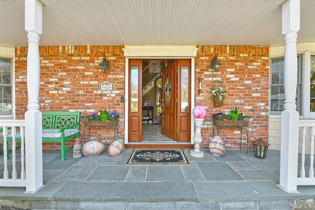 entrance to property with covered porch and brick siding