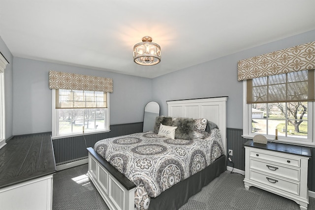bedroom with a wainscoted wall, a chandelier, and a baseboard heating unit