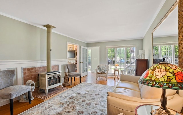living area featuring wood finished floors, a wood stove, and crown molding