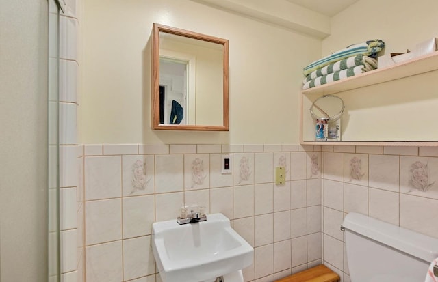 bathroom featuring toilet, a sink, and tile walls