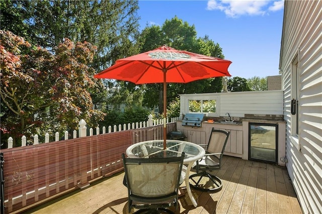 deck with a sink, exterior kitchen, wine cooler, grilling area, and outdoor dining space