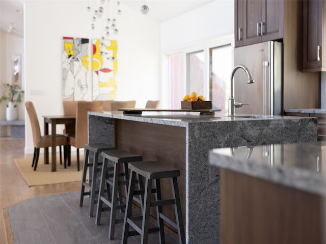 kitchen featuring light stone countertops, dark wood-style flooring, a breakfast bar, and freestanding refrigerator