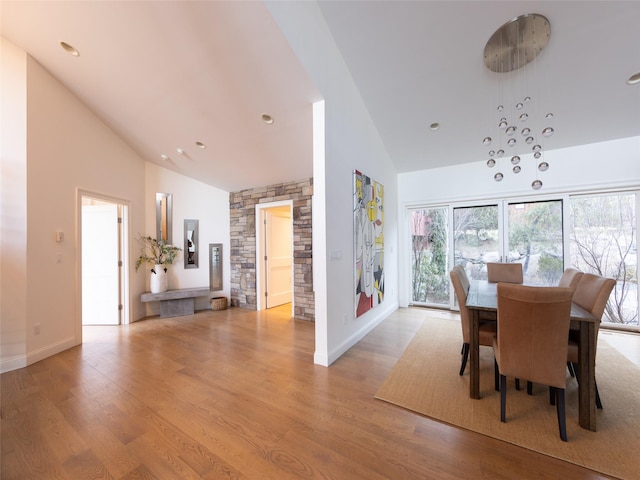 dining room with high vaulted ceiling, light wood-style floors, and baseboards