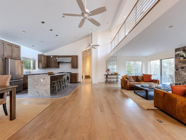 living area featuring light wood-type flooring, a towering ceiling, a ceiling fan, and recessed lighting