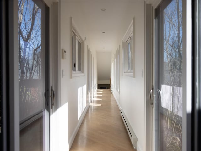 corridor featuring plenty of natural light, light wood finished floors, and a baseboard heating unit