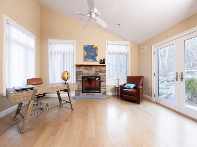 office space featuring visible vents, a stone fireplace, wood finished floors, and lofted ceiling