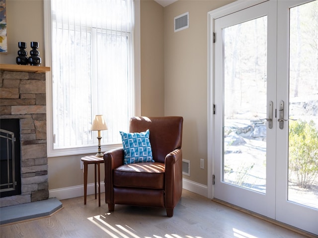 living area with a fireplace, visible vents, french doors, and a healthy amount of sunlight