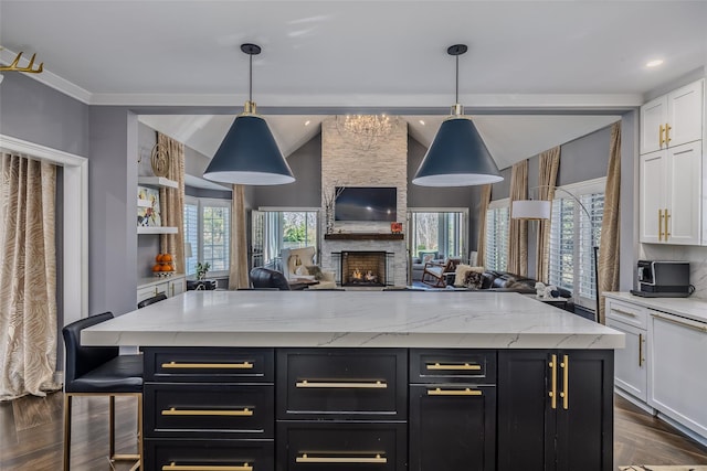 kitchen with open floor plan, white cabinets, light stone counters, and dark cabinets