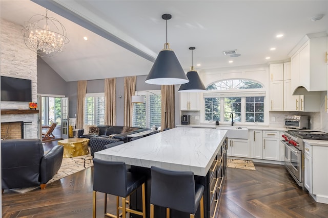 kitchen featuring a stone fireplace, light stone counters, open floor plan, range with two ovens, and a sink