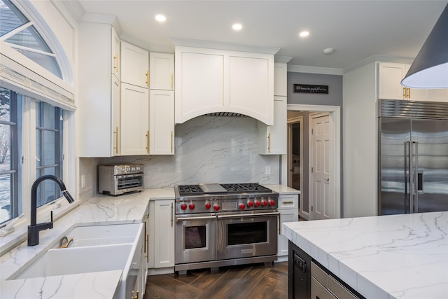 kitchen featuring white cabinets, a sink, high quality appliances, recessed lighting, and decorative backsplash