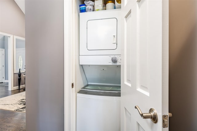 clothes washing area with stacked washer / drying machine, laundry area, and wood finished floors
