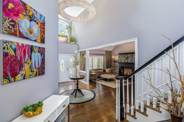 entryway featuring a wealth of natural light, stairway, a towering ceiling, and wood finished floors
