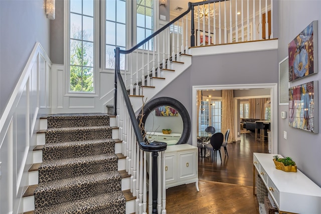 stairway with wood finished floors and a towering ceiling