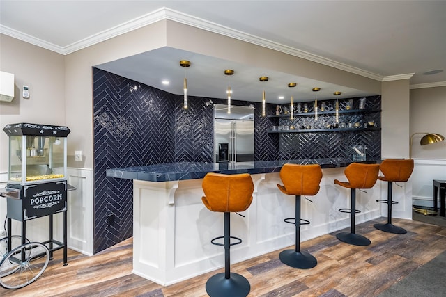 bar featuring bar area, built in fridge, crown molding, and wood finished floors
