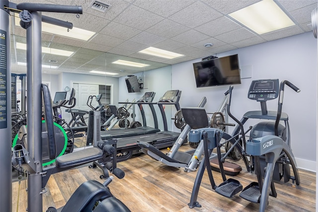 gym with wood finished floors, a drop ceiling, and visible vents