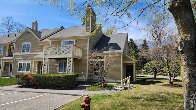 view of front of house featuring uncovered parking, a chimney, a balcony, and a front yard