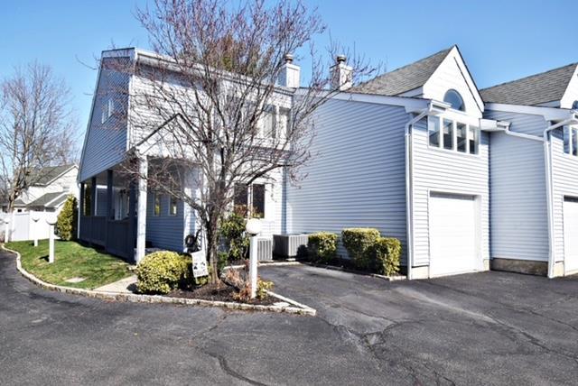 10 Windsor Ct, Amityville, NY 11701 - view of property exterior featuring driveway, a chimney, a garage, and cooling unit
