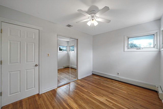 46 Arthur St, Brentwood, NY 11717 - unfurnished bedroom with a baseboard radiator, a closet, multiple windows, and wood-type flooring