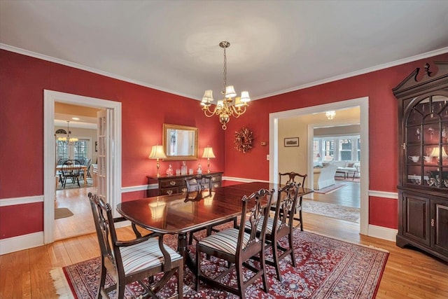 dining area featuring crown molding, baseboards, an inviting chandelier, and light wood-style floors
