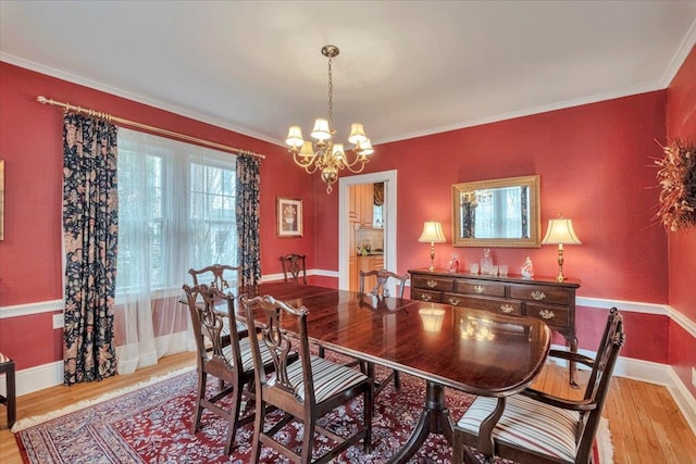 dining room featuring baseboards, ornamental molding, light wood-type flooring, and a chandelier