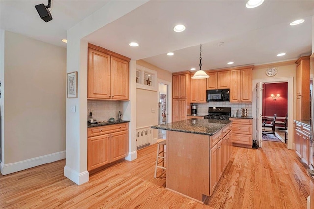 kitchen with a breakfast bar, baseboards, decorative backsplash, a kitchen island, and black appliances