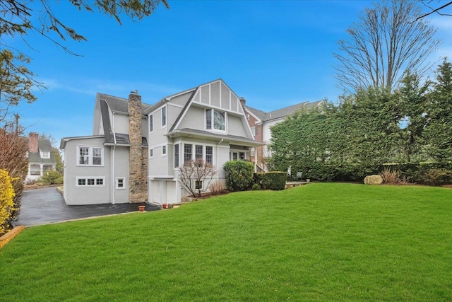 rear view of house featuring a yard and a chimney