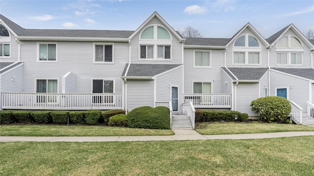 multi unit property with a front yard and roof with shingles