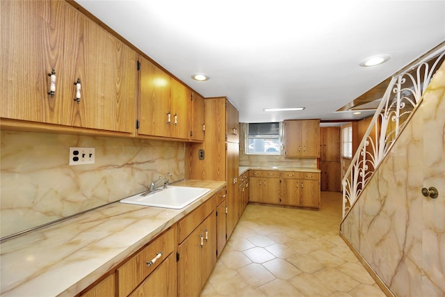 kitchen featuring light countertops, decorative backsplash, a sink, and brown cabinetry