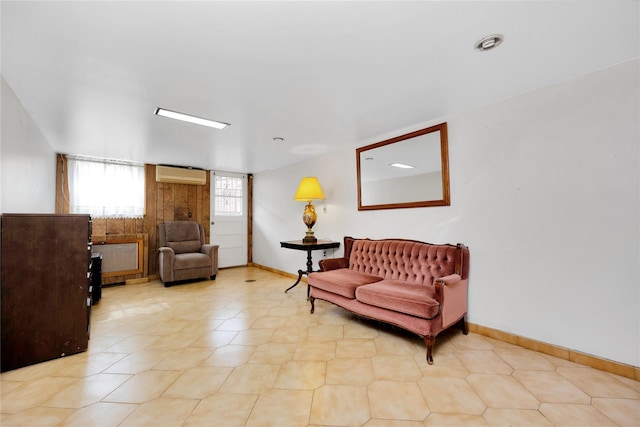 living area featuring baseboards and an AC wall unit
