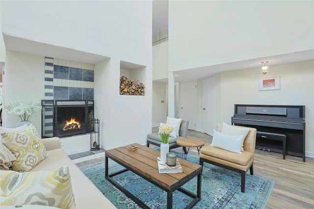 living area with baseboards, a high ceiling, wood finished floors, and a tile fireplace