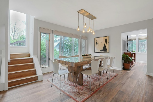 dining area with baseboards, wood finished floors, visible vents, and stairway