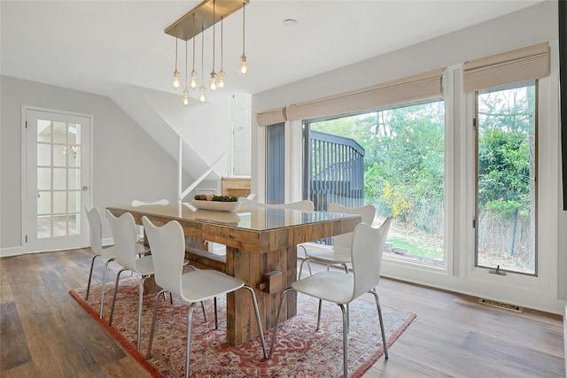 dining space featuring vaulted ceiling, wood finished floors, and visible vents