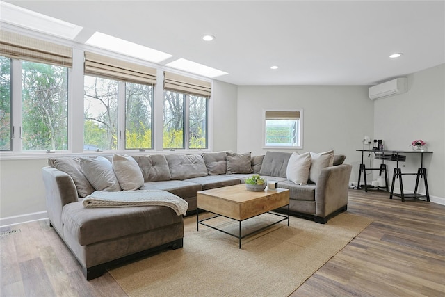 living room featuring an AC wall unit, recessed lighting, light wood-style flooring, and baseboards
