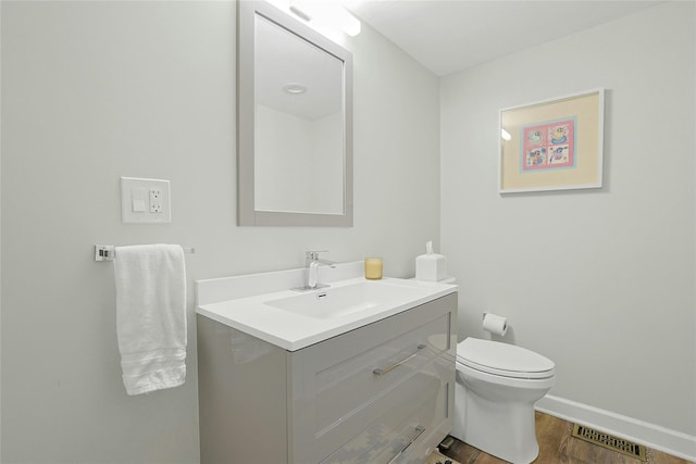 bathroom with vanity, visible vents, wood finished floors, toilet, and baseboards