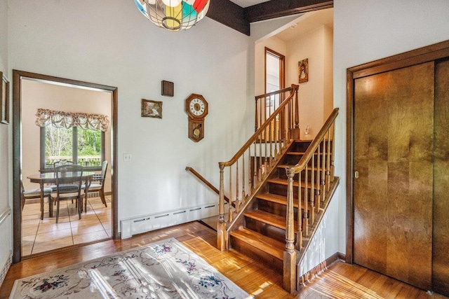 59 Giant Oak Rd, Ridge, NY 11961 - staircase featuring baseboard heating, wood finished floors, a high ceiling, beamed ceiling, and baseboards