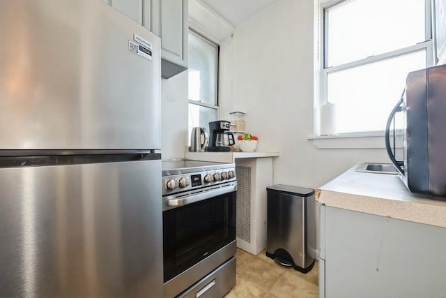 1185 E Broadway Unit 4A, Hewlett, NY 11557 - kitchen featuring light countertops, a healthy amount of sunlight, light tile patterned floors, and appliances with stainless steel finishes
