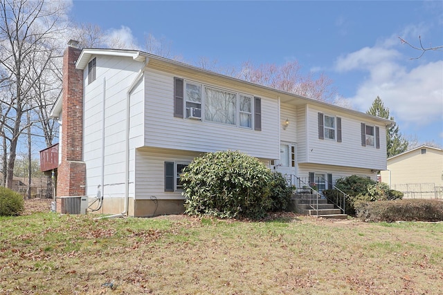 split foyer home featuring a front yard, central AC unit, cooling unit, and a chimney