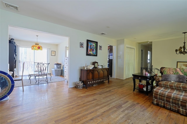 living area featuring a chandelier, wood finished floors, baseboards, and visible vents